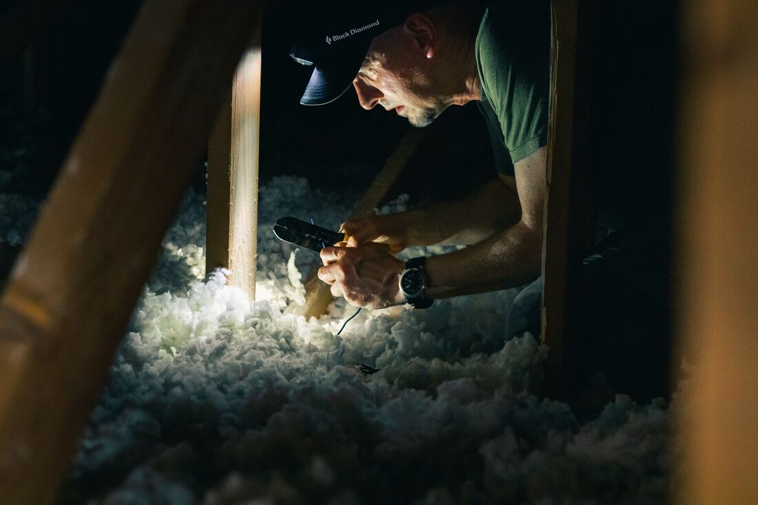 A worker is doing insulation installation in the crawl space